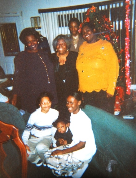 A family Christmas photo: Anthony's mother Crystal standing with her mother, sister, and the children — a Christmas tree behind them, everyone gathered close.
