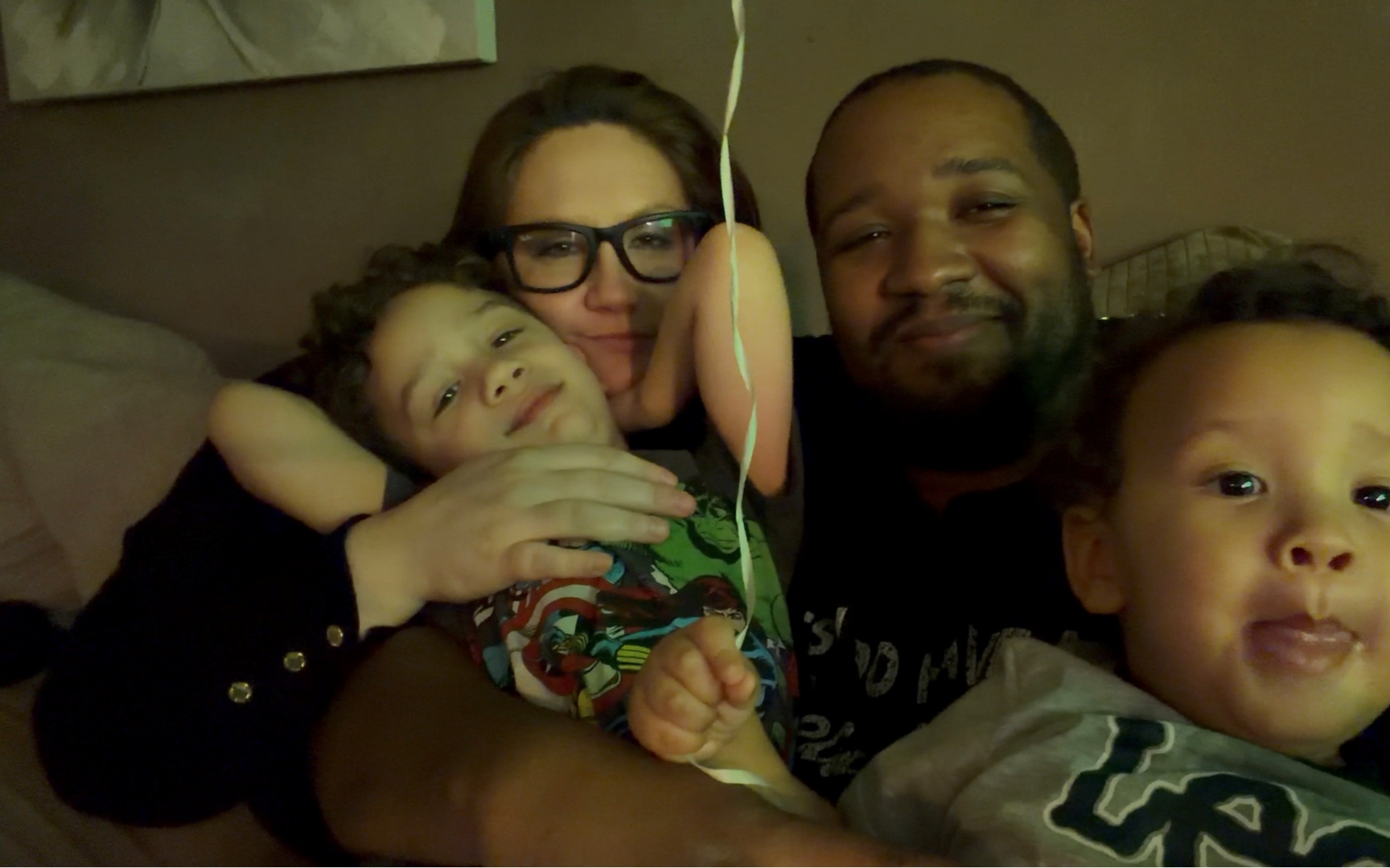 Family snuggled together in bed with kids.