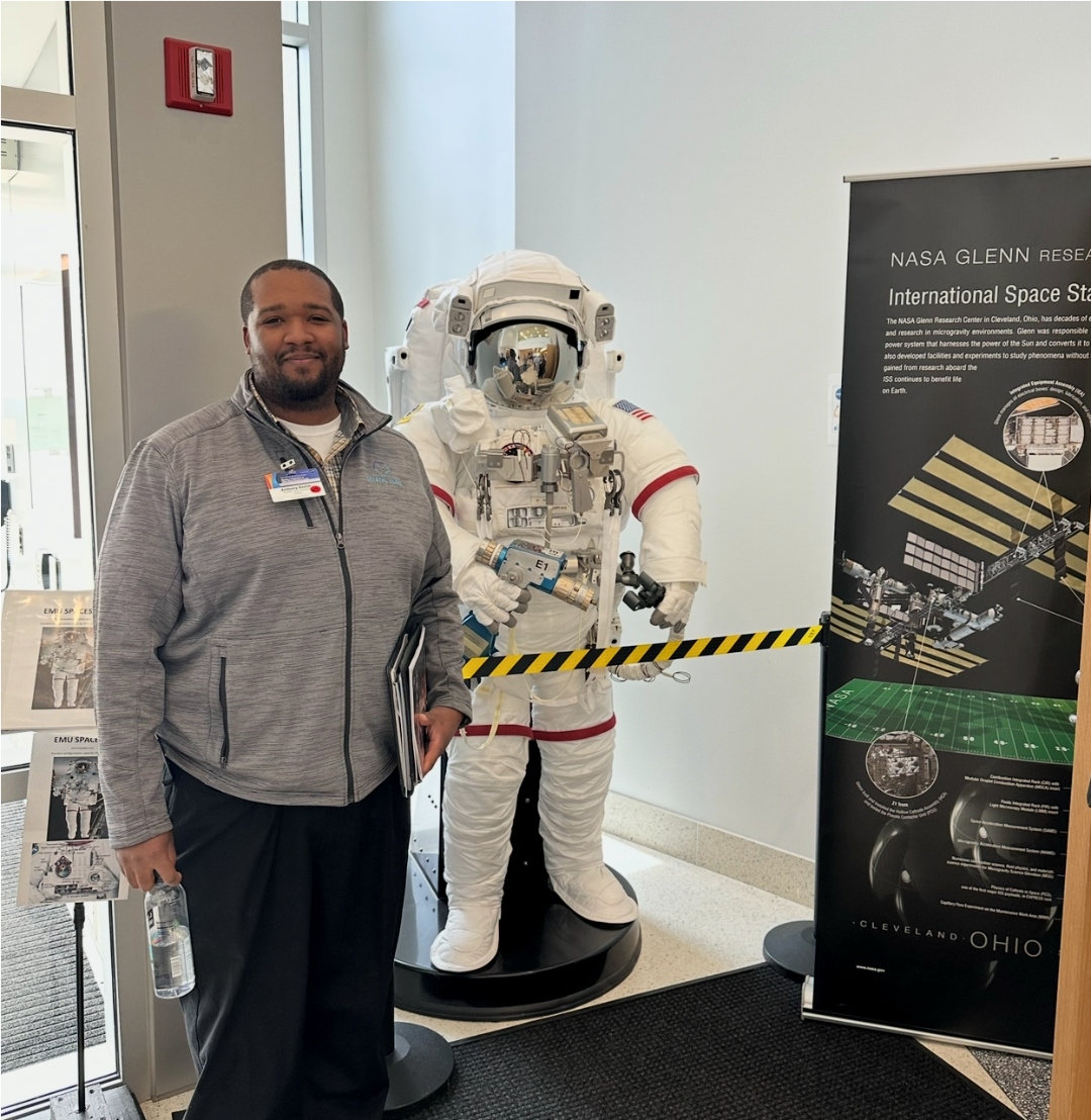 Anthony standing next to an EMU spacesuit display at NASA Glenn Research Center.