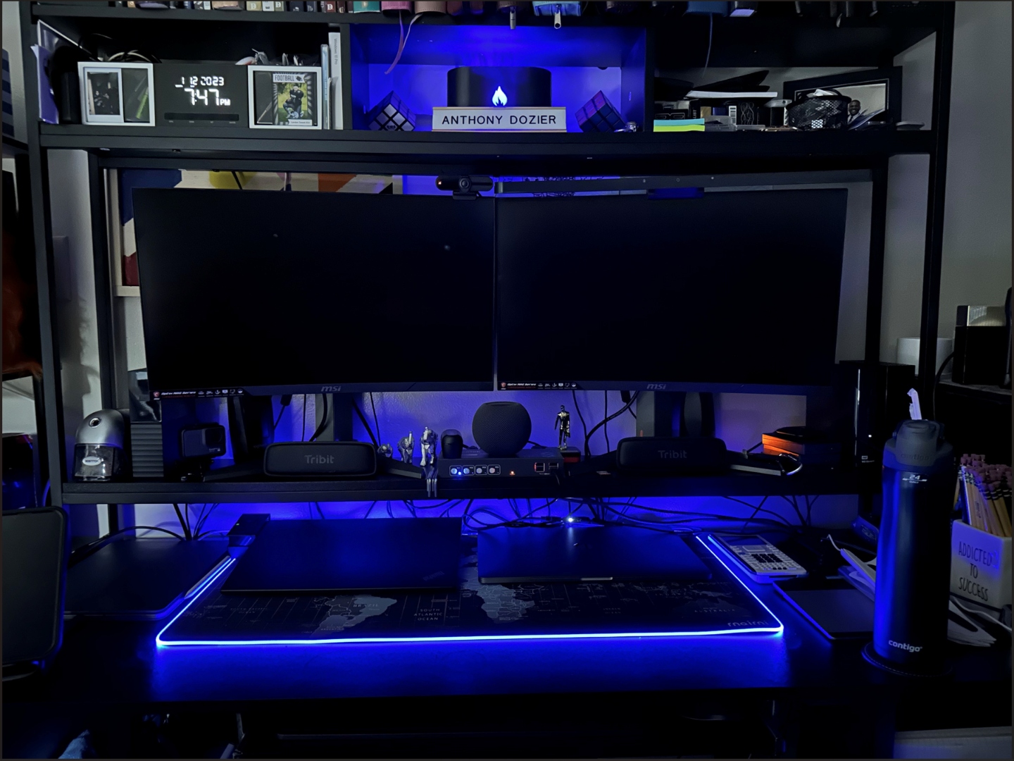 Dual-monitor home AI lab workstation with curved displays, blue ambient lighting, and a name plate reading Anthony Dozier.